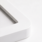 Close-up of a white rectangular object with rounded edges on a light gray background